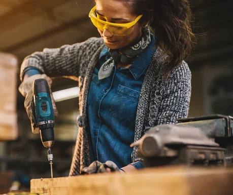 woman using a drill in a wood shop